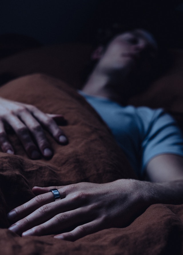 Ein Mann liegt schlafend im Bett und trägt den Oura Ring 4 Silver