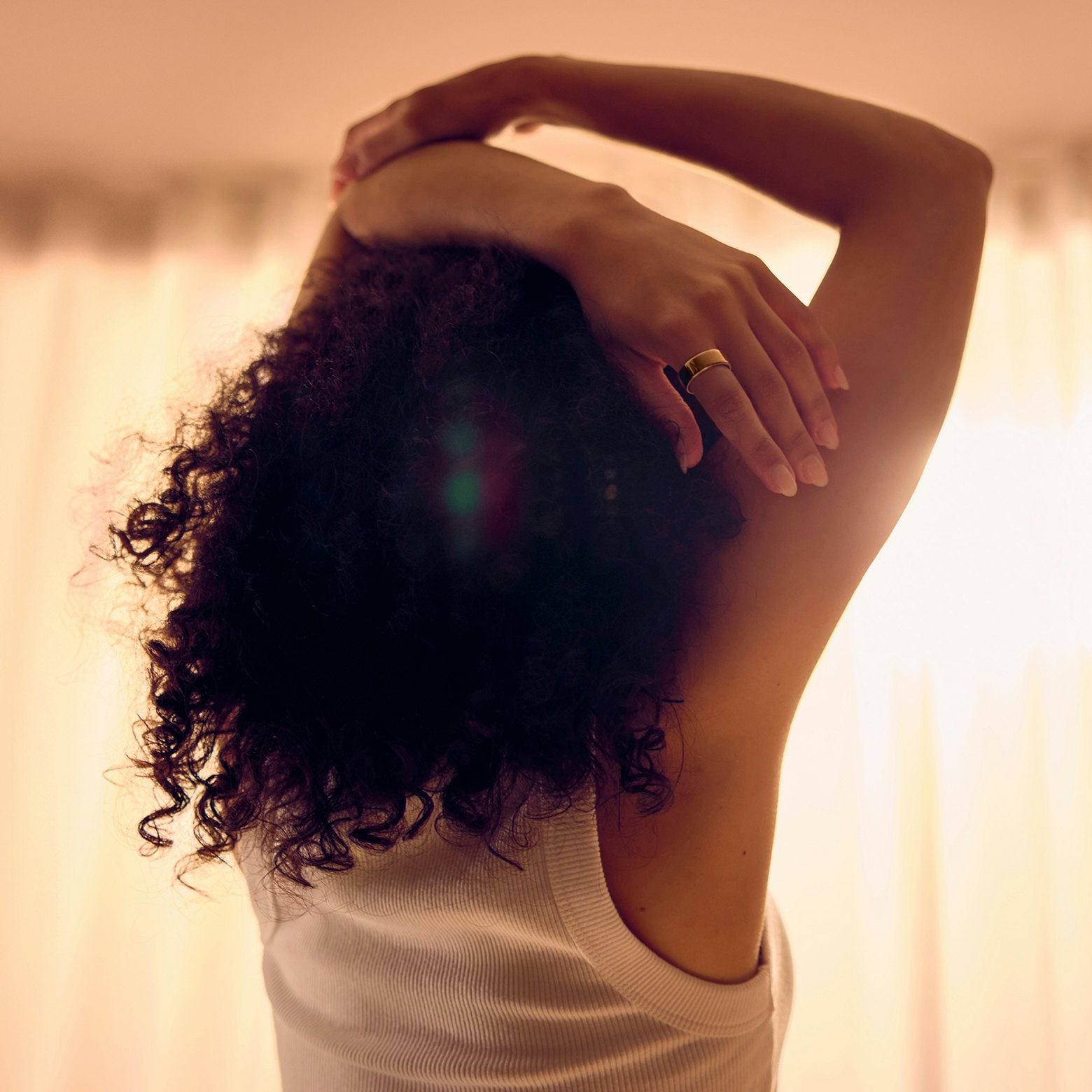 Frau trägt einen Oura Ring und streckt ihre Hände über den Kopf