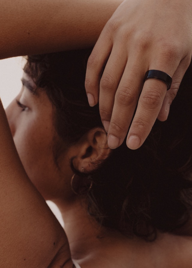 Frau mit über dem Kopf verschränkten Armen trägt den Oura Ring 4 Black