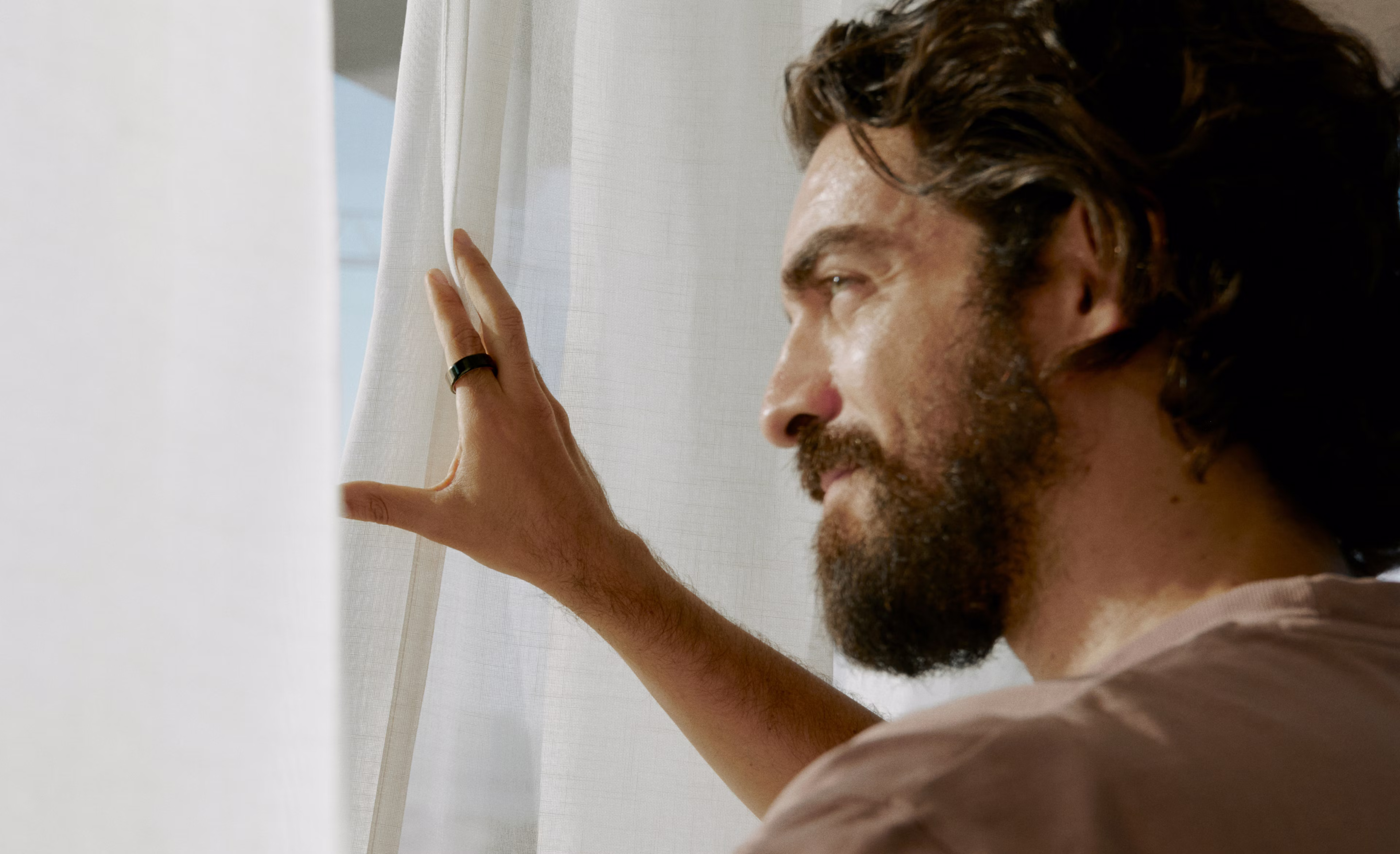 Mann blickt aus dem Fenster und trägt einen Oura Ring