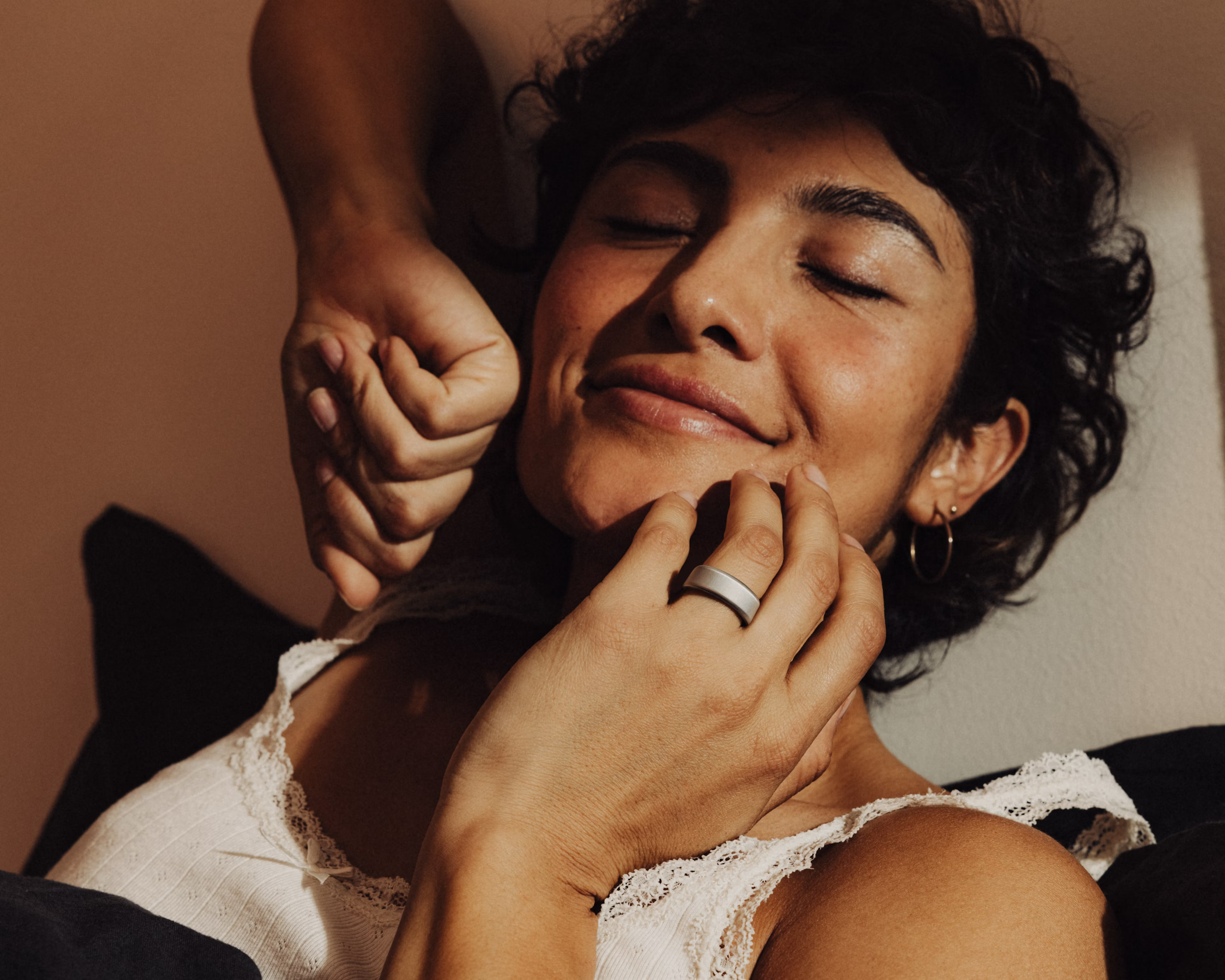 Nahaufnahme einer Frau, die Dehnübungen macht und an der Hand an ihrem Gesicht einen Oura Ring trägt.